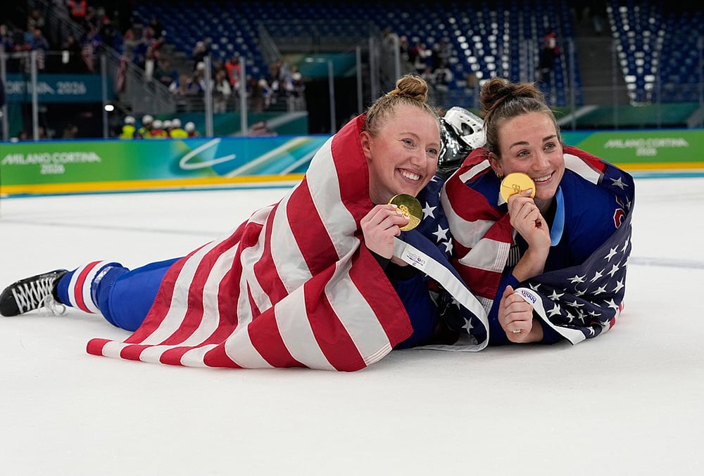 United States' Grace Zumwinkle, left, and Taylor Heise celebrate after victory ceremony for women's ice hockey at the 2026 Winter Olympics, in Milan, Italy. - | Photo: AP/Hassan Ammar