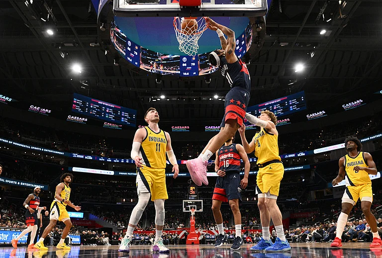 Washington Wizards guard Alondes Williams (31) reverse dunks over Indiana Pacers center Micah Potter (11) and guard Taelon Peter (4) during the second half of an NBA basketball game in Washington. - | Photo: AP/Nick Wass