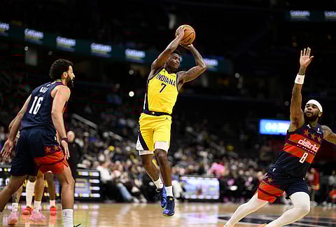 Indiana Pacers guard Kam Jones (7) looks to pass the ball against Washington Wizards forward Anthony Gill (16) and guard Jaden Hardy (8) during the first half of an NBA basketball game, in Washington.