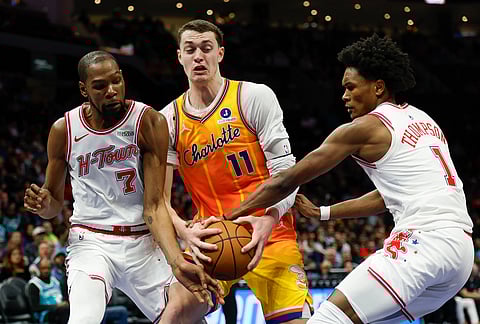 Charlotte Hornets center Ryan Kalkbrenner (11) battles Houston Rockets forward Kevin Durant (7) and guard Amen Thompson (1) for the ball during the second half of an NBA basketball game in Charlotte, North Carolina.