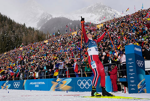 Johannes Dale-Skjevdal, of Norway, crosses the finish line to win gold in the men's 15-kilometer mass start biathlon race at the 2026 Winter Olympics in Anterselva, Italy.
