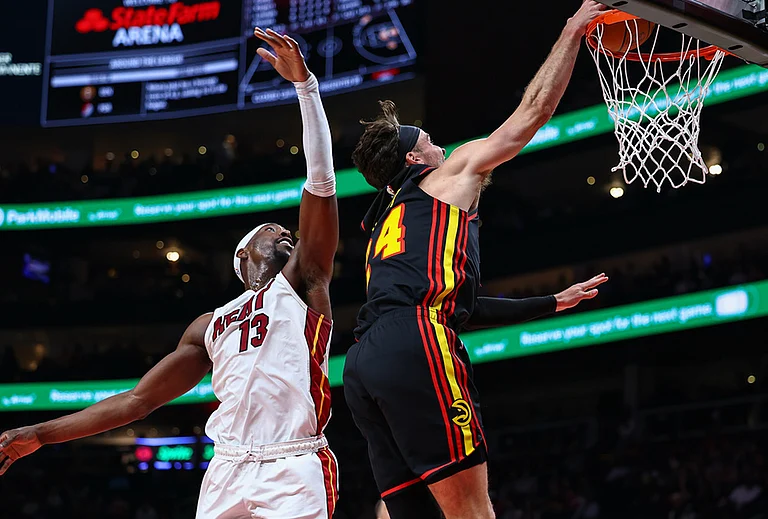 Atlanta Hawks forward Corey Kispert, right, dunks against Miami Heat center Bam Adebayo, left, during the first half of an NBA basketball game, in Atlanta. - | Photo: AP/Colin Hubbard
