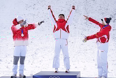 From left, silver medalist Switzerland's Noe Roth, gold medalist China's Wang Xindi and bronze medalist China's Li Tianma celebrate after the men's freestyle skiing aerials finals at the 2026 Winter Olympics, in Livigno, Italy.