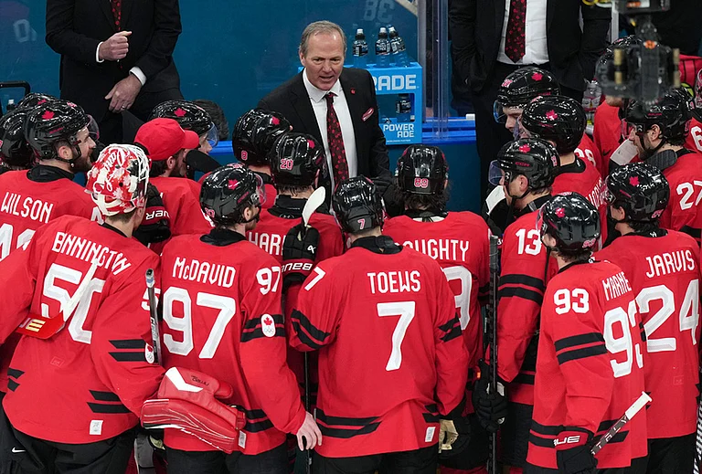 Canada head coach Jon Cooper talks with his players after their win against Finland in a men's ice hockey semifinal game at the 2026 Winter Olympics in Milan, Italy. - | Photo: AP/Carolyn Kaster