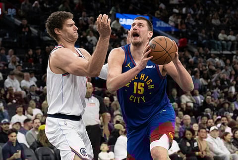Denver Nuggets center Nikola Jokic, right, drives to the basket as Los Angeles Clippers center Brook Lopez defends during the second half of an NBA basketball game in Inglewood, California.