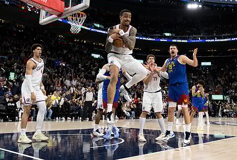 Los Angeles Clippers forward John Collins, center, grabs a rebound from a free throw miss by Denver Nuggets guard Jamal Murray during the second half of an NBA basketball game in Inglewood, California.