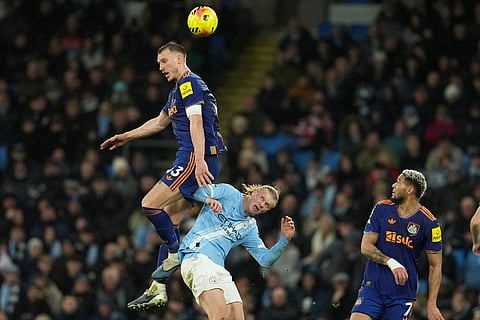Newcastle's Dan Burn, lrft, and Manchester City's Erling Haaland fight for the ball during the English Premier League soccer match between Manchetser City and Newcastle in Manchester, England.