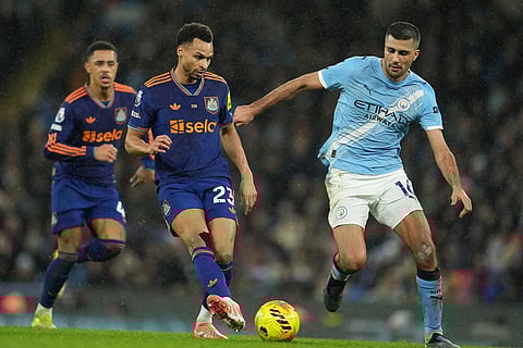 Newcastle's Jacob Murphy passes the ball in front of Manchester City's Rodrigo during the English Premier League soccer match between Manchetser City and Newcastle in Manchester, England.