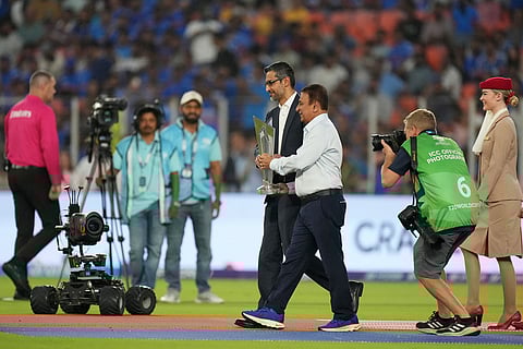 Former India international Sunil Gavaskar, center right, and Google CEO Sundar Pichai carry the tournament trophy jointly before the start of the T20 World Cup cricket match between India and South Africa in Ahmedabad, India.
