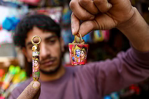 A shopkeeper shows miniatures of a bucket and a water gun ahead of the 'Holi' festival, in Jammu.
