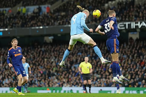 Manchester City's Erling Haaland, left, and Newcastle's Dan Burn jump for the ball during the English Premier League soccer match between Manchetser City and Newcastle in Manchester, England.