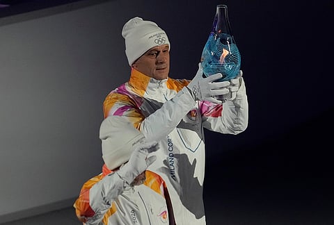 The Olympic flame is carried during the closing ceremony of the 2026 Winter Olympics, in Verona, Italy.