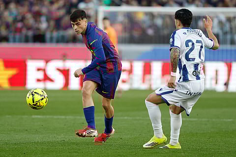 Barcelona's Pedri passes the ball by Levante's Paco Cortes during a La Liga soccer match between Barcelona and Levante in Barcelona, Spain.