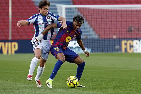 Levante's Carlos Alvarez holds Barcelona's Lamine Yamal during a La Liga soccer match between Barcelona and Levante in Barcelona, Spain.