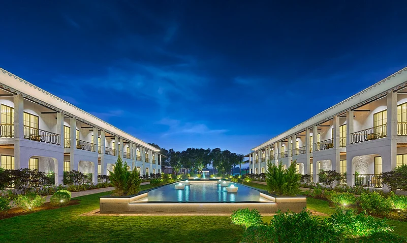 Digital rendering of a luxury white two-story resort surrounding a central pool at dusk