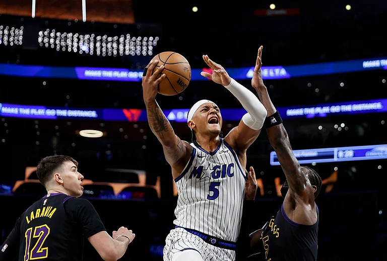 Orlando Magic forward Paolo Banchero (5) drives to the basket with the ball while being guarded by Los Angeles Lakers forward Jake LaRavia (12) and Los Angeles Lakers center Deandre Ayton (5) during the first half of an NBA basketball game in Los Angeles. - | Photo: AP/Caroline Brehman