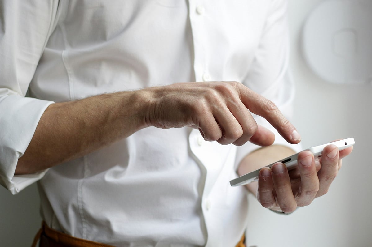 Close-up of person in white shirt using smartphone.