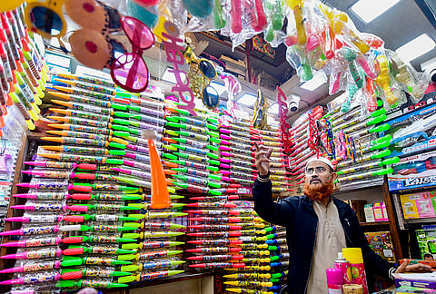 A shopkeeper sells water guns and other items ahead of the Holi festival, in Guwahati. 