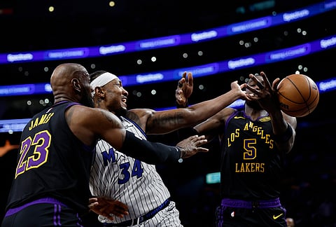 Orlando Magic center Wendell Carter Jr. (34) loses control of the ball while being guarded by Los Angeles Lakers forward LeBron James (23) and Los Angeles Lakers center Deandre Ayton (5) during the first half of an NBA basketball game in Los Angeles. 