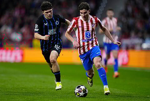 Atletico Madrid's Julian Alvarez, right, controls the ball as Brugge's Kyriani Sabbe tries to stop him during the Champions League play-off second leg soccer match between Atletico Madrid and Club Brugge, in Madrid, Spain.