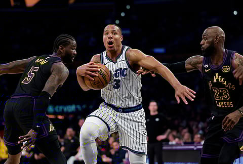 Orlando Magic guard Desmond Bane (3) dribbles with the ball past Los Angeles Lakers center Deandre Ayton (5) and Los Angeles Lakers forward LeBron James (23) during the first half of an NBA basketball game, in Los Angeles.