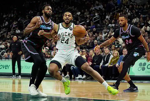 Milwaukee Bucks' Cam Thomas, middle, drives to the basket between Miami Heat's Andrew Wiggins, left, and Norman Powell, right, during the first half of an NBA basketball game, in Milwaukee.