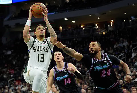 Milwaukee Bucks' Ryan Rollins (13) shoots past Miami Heat's Norman Powell during the first half of an NBA basketball game in Milwaukee.