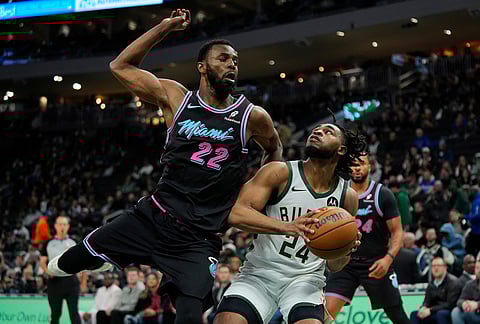 Milwaukee Bucks' Cam Thomas (24) looks to shoot past Miami Heat's Andrew Wiggins during the first half of an NBA basketball game in Milwaukee.