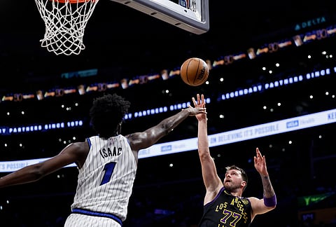 Los Angeles Lakers guard Luka Doncic (77) shoots the ball while being guarded by Orlando Magic forward Jonathan Isaac (1) during the second half of an NBA basketball game in Los Angeles. 