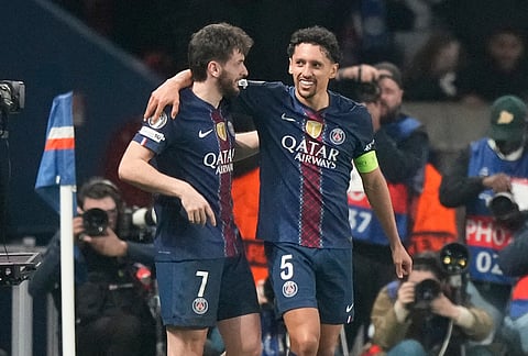 PSG's Khvicha Kvaratskhelia.left, and Marquinhos hug after a goal during a Champions League second leg playoff soccer match between Paris Saint-Germain and Monaco in Paris.
