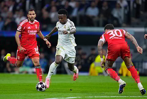 Real Madrid's Vinicius Junior, center, and Benfica's Nicolas Otamendi, right, challenge for the ball during the second leg of the Champions League playoff soccer match between Real Madrid and Benfica in Madrid, Spain.