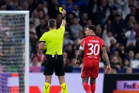 Referee Slavko Vincic shows a yellow card to Benfica's Nicolas Otamendi during the second leg of the Champions League playoff soccer match between Real Madrid and Benfica in Madrid, Spain.