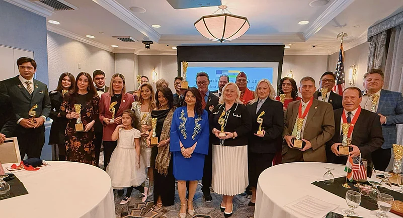 Captain Arun Kar and Nidhi Kar holding awards at formal ceremony in New York with honorees
