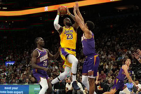 Los Angeles Lakers forward LeBron James drives between Phoenix Suns forward Rasheer Fleming (20) and forward Oso Ighodaro during the first half of an NBA basketball game in Phoenix.
