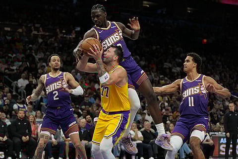 Los Angeles Lakers guard Luka Doncic drives between Phoenix Suns guard Amir Coffey (2), center Khaman Maluach, and forward Oso Ighodaro (11) during the second half of an NBA basketball game in Phoenix.