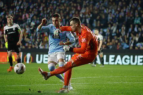 PAOK's goalkeeper Antonis Tsiftsis, right, kicks the ball next to Celta's Ferran Jutgla during the second leg of the Europa League playoff soccer match between Celta Vigo and PAOK in Vigo, Spain.