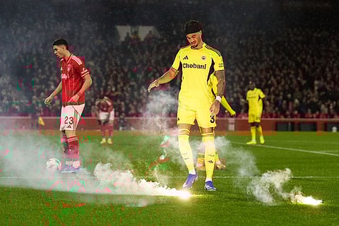 Fenerbahce's Archie Brown removes a flare thrown on the pitch during the Europa League knockout phase play-off second leg match between Nottingham Forest and Fenerbahce in Nottingham, England.