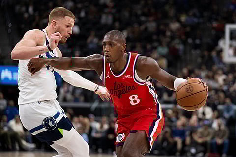 Los Angeles Clippers guard Kris Dunn, right, drives to the basket as Minnesota Timberwolves guard Donte DiVincenzo, left, defends during the first half of an NBA basketball game in Inglewood, Calif.