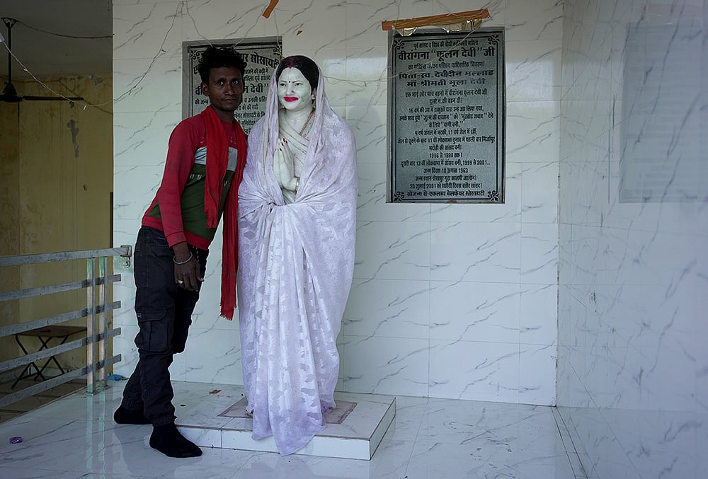Anmol, a local villager takes us to the house of Phoolan Devi in Shekhpur Guda. As he unveils the Statue from its “ghoongat”, he stops to pose with it for the camera - | Photo:  Animikh Chakrabarty/Outlook