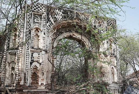 A gateway, closed off, beyond which lies the abandoned houses of families that left the village after the Behmai massacre