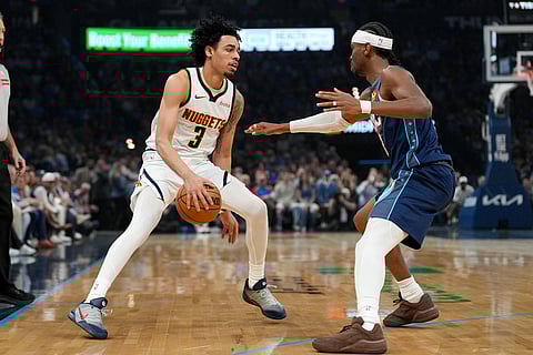 Denver Nuggets guard Julian Strawther, left, looks for an opening past Oklahoma City Thunder guard Shai Gilgeous-Alexander, right, during the first half of an NBA basketball game in Oklahoma City.
