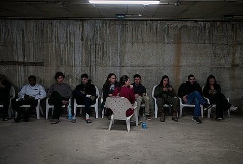 People sits in a shelter after warning sirens sound following Israeli strikes on Iran, in Tel Aviv, Israel.