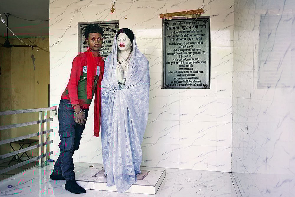The Devi Incarnation: Anmol, a resident of Sheikhpur Gurha village in Jalaun district, Uttar Pradesh, next to Phoolan Devi’s statue at the entrance of her home in the village - | Photo: Animikh Chakrabarty