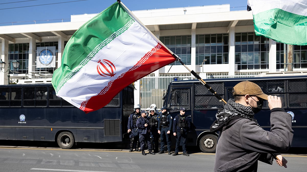 A protester waves an Iranian flag during a rally against U.S. and Israeli strikes on Iran, outside the U.S. embassy in Athens, Greece, Sunday, Mar. 1, 2026. - | Photo: AP/Yorgos Karahalis