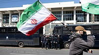 US‑Iran War: FIFA Wants A Safe World Cup 2026 With ‘All Teams Participating’ | Photo: AP/Yorgos Karahalis : A protester waves an Iranian flag during a rally against U.S. and Israeli strikes on Iran, outside the U.S. embassy in Athens, Greece, Sunday, Mar. 1, 2026.