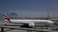 Altaf Qadri : A plume of smoke caused by an Iranian strike is seen in the background an an Emirates plane is parked at the Dubai International Airport after its closure in Dubai, United Arab Emirates, Sunday, March 1, 2026.