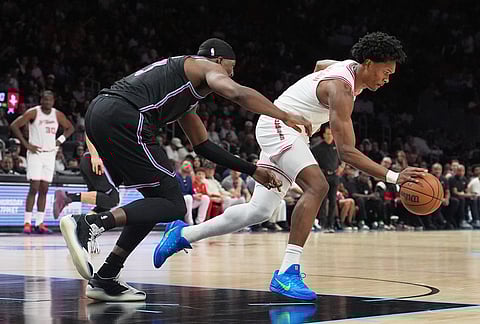 Houston Rockets guard Amen Thompson, right, grabs a loose ball from Miami Heat center Bam Adebayo, left, during the first half of an NBA basketball game, in Miami.