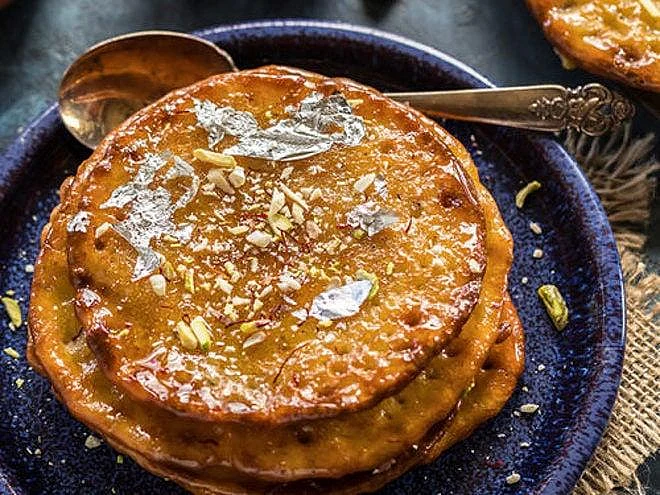 Fried malpua pancakes with silver leaf
