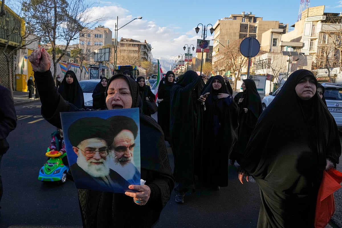 A woman holds pictures of Ayatollah Khomeini and the late Iranian Supreme Leader Ayatollah Ali Khamenei as a group of government supporters march toward Khamenei's residency in Tehran, Iran, Sunday, March 1, 2026, following the confirmed death of Khamenei in U.S. and Israeli strikes - AP Photo/Vahid Salemi