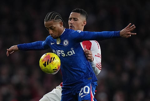 Chelsea's Joao Pedro, front, and Arsenal's William Saliba fight for the ball during the Premier League soccer match between Chelsea Arsenal in London.